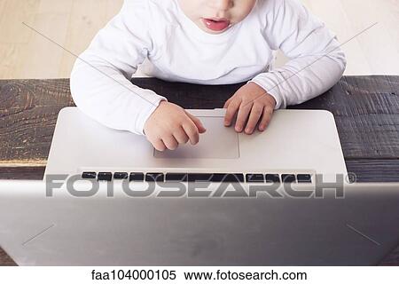 Stock Photography - Little boy using laptop computer, cropped. Fotosearch