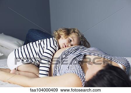 Little girl and pregnant mother lying together on bed View Large Photo Image Stock Photo - Little girl and pregnant mother lying together on bed. Fotosearch
