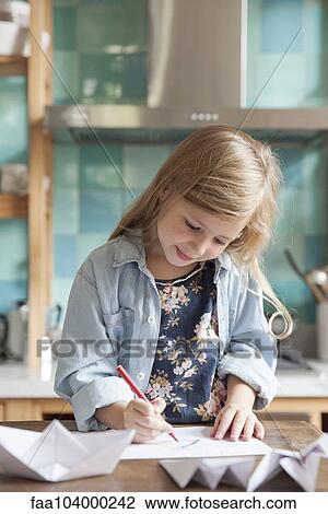Stock Image - Little girl drawing in kitchen, portrait. Fotosearch