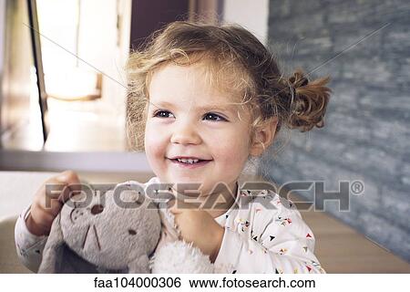 Stock Photograph - Little girl holding stuffed toy, smiling, portrait. Fotosearch