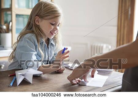 Stock Photograph - Little girl learning how to make paper airplane. Fotosearch