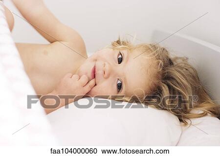 Little girl lying down with finger in mouth, portrait View Large Photo Image Stock Image - Little girl lying down with finger in mouth, portrait. Fotosearch