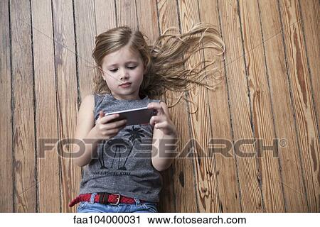 Little girl lying on floor using smartphone View Large Photo Image Stock Image - Little girl lying on floor using smartphone. Fotosearch