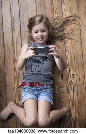 Little girl lying on floor using smartphone View Large Photo Image Stock Photo - Little girl lying on floor using smartphone. Fotosearch