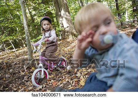 Little girl riding bike in wooded area View Large Photo Image Stock Image - Little girl riding bike in wooded area. Fotosearch