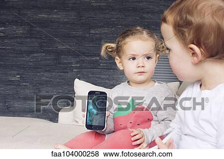 Little girl showing smartphone to her brother View Large Photo Image Stock Photo - Little girl showing smartphone to her brother. Fotosearch