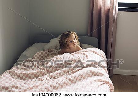 Stock Image - Little girl sitting in bed. Fotosearch