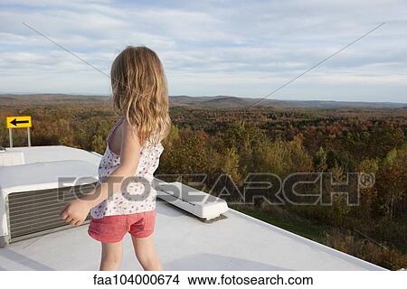 Picture - Little girl standing on top of motor home, looking at scenic view. Fotosearch