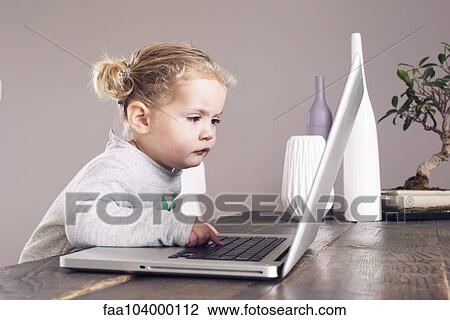 Stock Image - Little girl using laptop computer. Fotosearch