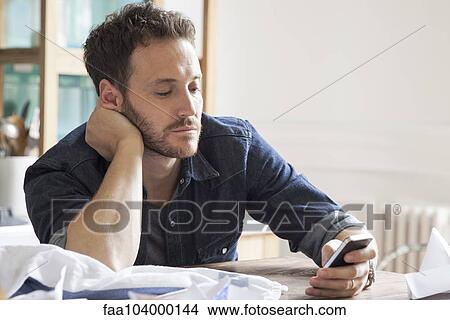 Man at home using smartphone View Large Photo Image Picture - Man at home using smartphone. Fotosearch