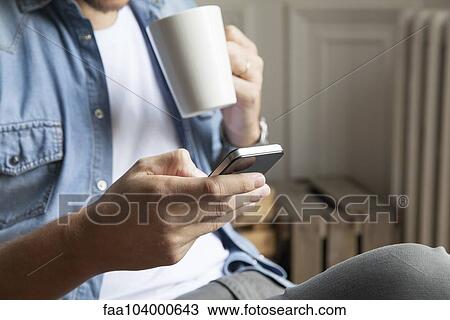 Stock Image - Man catching up with emails while having morning coffee. Fotosearch