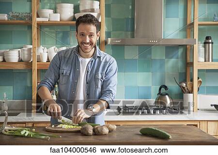 Man cutting up ingredients in kitchen, portrait View Large Photo Image Stock Photograph - Man cutting up ingredients in kitchen, portrait. Fotosearch