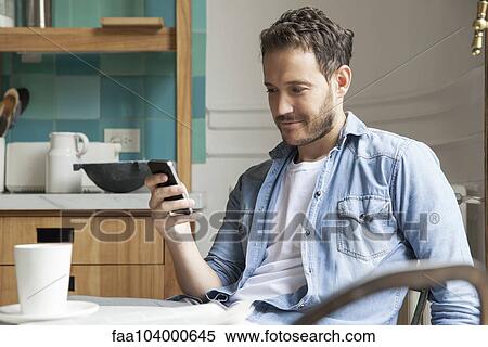 Man reading news on smartphone while having breakfast View Large Photo Image Stock Photography - Man reading news on smartphone while having breakfast. Fotosearch