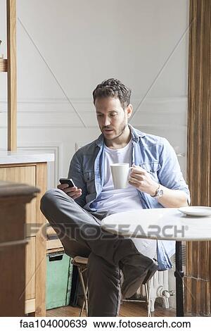 Stock Photo - Man sending text message during coffee break. Fotosearch