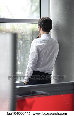 Man using phone looking out window View Large Photo Image Stock Photography - Man using phone looking out window. Fotosearch
