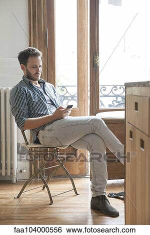Man using smartphone at home View Large Photo Image Stock Photograph - Man using smartphone at home. Fotosearch