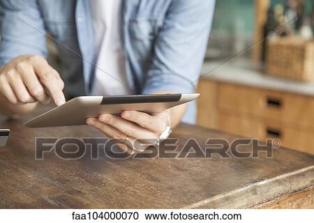 Stock Image - Man using wireless device at home. Fotosearch