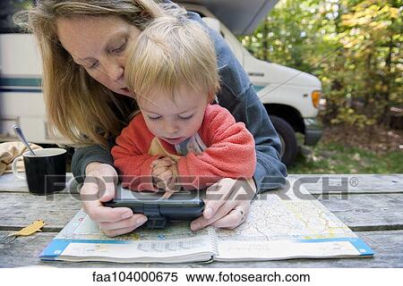Mother holding child on lap while using atlas and GPS to plan road trip View Large Photo Image Stock Photography - Mother holding child on lap while using atlas and GPS to plan road trip. Fotosearch