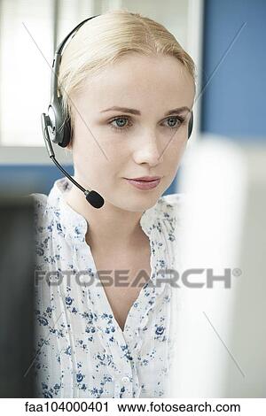 Stock Image - Operator wearing headset at work. Fotosearch