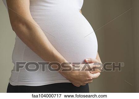 Stock Photo - Pregnant woman cradling abdomen. Fotosearch