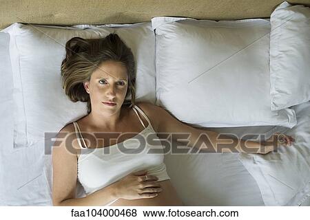 Pregnant woman lying in bed alone View Large Photo Image Stock Photo - Pregnant woman lying in bed alone. Fotosearch