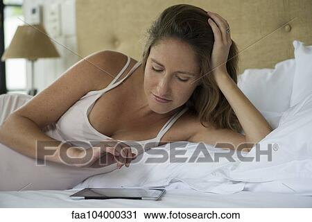 Pregnant woman lying in bed using digital tablet View Large Photo Image Stock Image - Pregnant woman lying in bed using digital tablet. Fotosearch