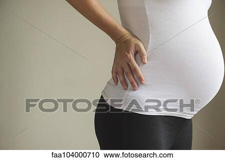 Pregnant woman massaging lower back View Large Photo Image Stock Image - Pregnant woman massaging lower back. Fotosearch