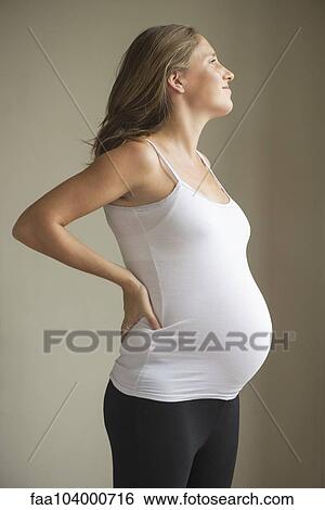 Stock Photograph - Pregnant woman massaging lower back. Fotosearch