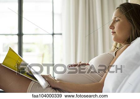 Pregnant woman reading magazine in bed View Large Photo Image Stock Photo - Pregnant woman reading magazine in bed. Fotosearch