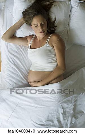 Stock Image - Pregnant woman sleeping in bed. Fotosearch