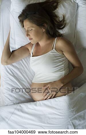 Stock Photo - Pregnant woman sleeping in bed. Fotosearch