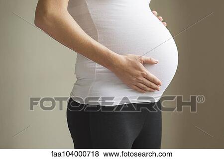 Stock Photo - Pregnant woman touching abdomen. Fotosearch