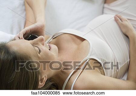 Stock Photography - Pregnant woman using cell phone to stay in touch with friends and family. Fotosearch