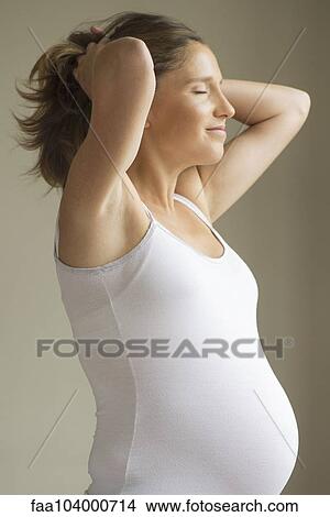 Pregnant woman with hands behind head View Large Photo Image Picture - Pregnant woman with hands behind head. Fotosearch
