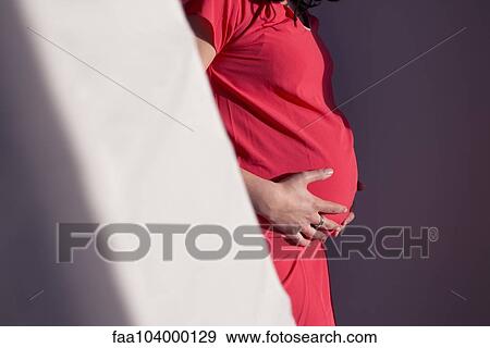 Stock Photo - Pregnant woman with hands on stomach, cropped. Fotosearch