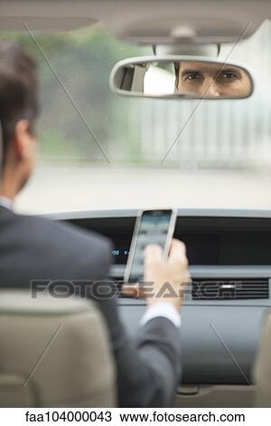 Stock Image - Using cell phone while driving car. Fotosearch