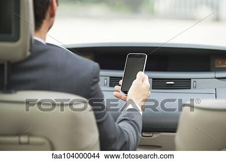 Picture - Using smartphone while driving. Fotosearch