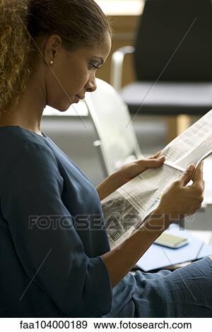 Stock Photo - Woman reading newspaper in waiting room. Fotosearch