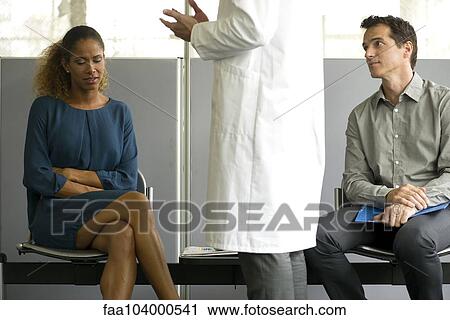 Stock Image - Woman receiving bad news from doctor in waiting room. Fotosearch