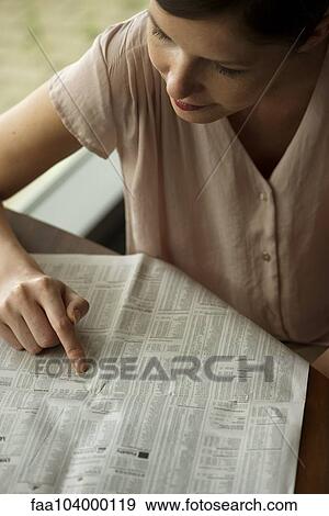 Stock Photo - Woman shopping for real estate in newspaper classified ads. Fotosearch
