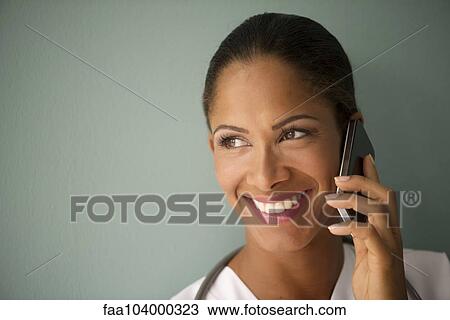 Stock Image - Woman talking on cell phone, smiling cheerfully. Fotosearch