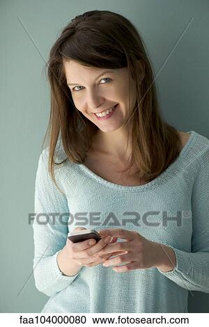 Stock Image - Woman using smartphone to stay connected. Fotosearch