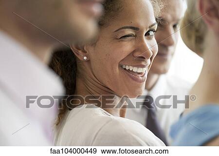 Woman with colleagues, winking playfully at camera View Large Photo Image Stock Photo - Woman with colleagues, winking playfully at camera. Fotosearch