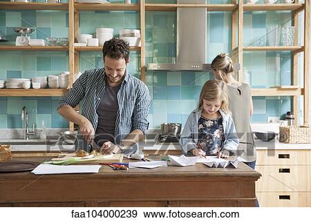 Young daughter drawing ar kitchen counter while parents prepare meal View Large Photo Image Stock Photo - Young daughter drawing ar kitchen counter while parents prepare meal. Fotosearch