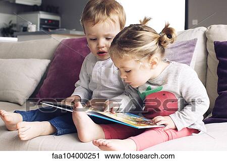 Young siblings looking at book together View Large Photo Image Stock Image - Young siblings looking at book together. Fotosearch
