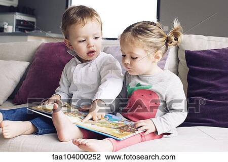 Young siblings looking at book together View Large Photo Image Stock Image - Young siblings looking at book together. Fotosearch