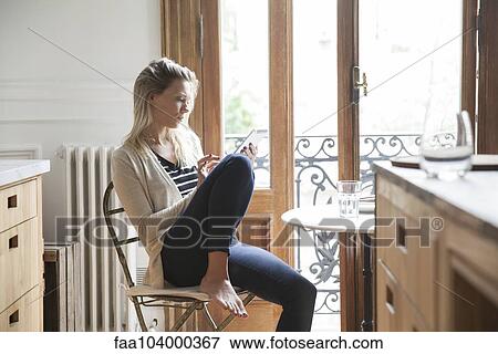Stock Photo - Young woman using digital tablet at home. Fotosearch