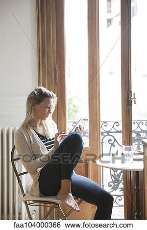 Stock Photograph - Young woman using digital tablet at home. Fotosearch