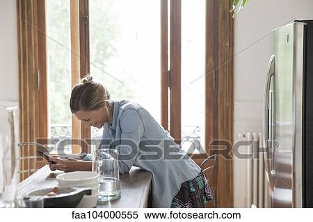 Young woman using smartphone in kitchen View Large Photo Image Stock Photography - Young woman using smartphone in kitchen. Fotosearch