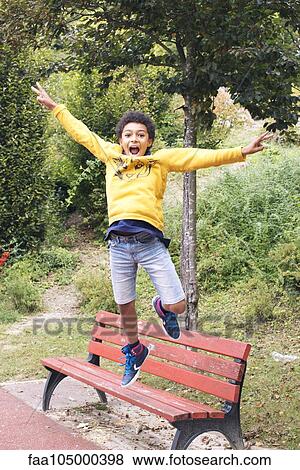 Boy jumping off bench View Large Photo Image Stock Photo - Boy jumping off bench. Fotosearch